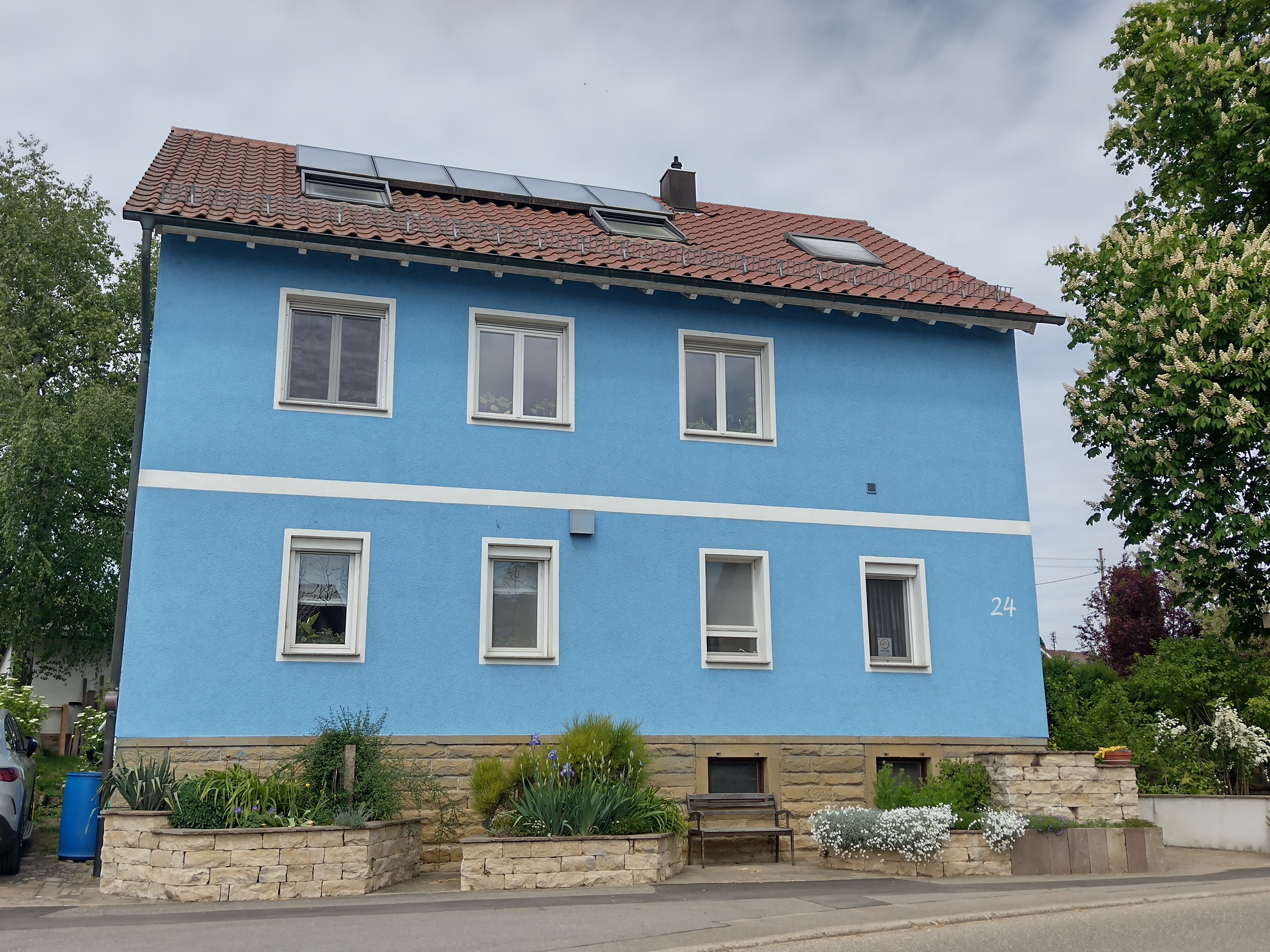 Foto des blauen Hauses neben einer großen Kastanie